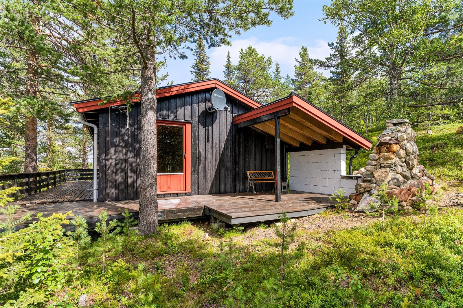 Hytta har en koselig uteplass med noe takoverbygg og utepeis. Galleribilde