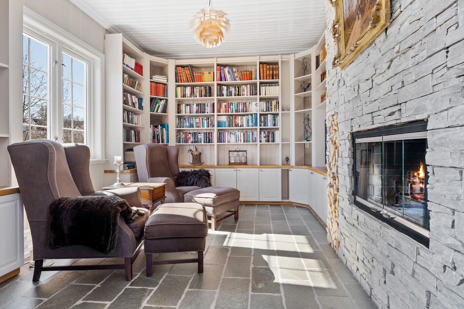 Fra hovedstuen kommer du også inn i boligens bibliotek. Her kan du nyte en bok foran den flotte peisen. Galleribilde
