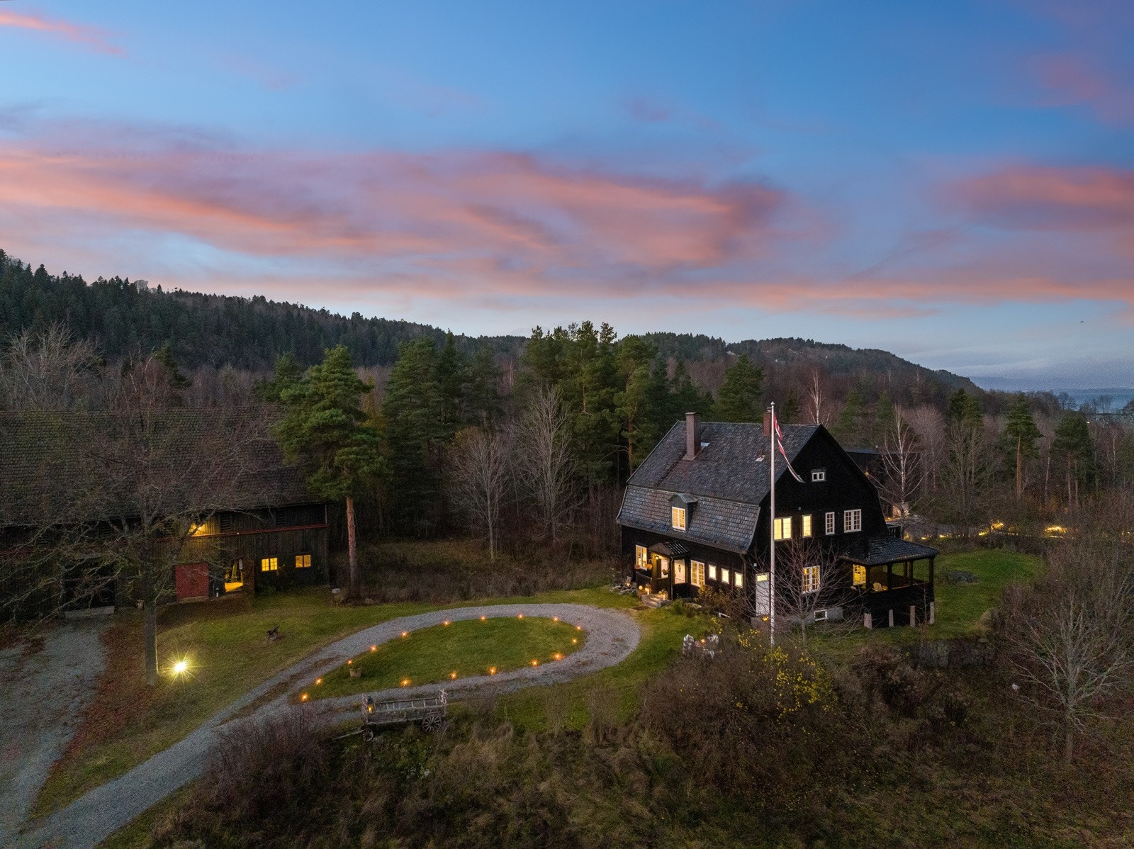 Den store tomten er på hele 13,5 mål. Her med stall og låvebygg på venstre side i bildet. Galleribilde