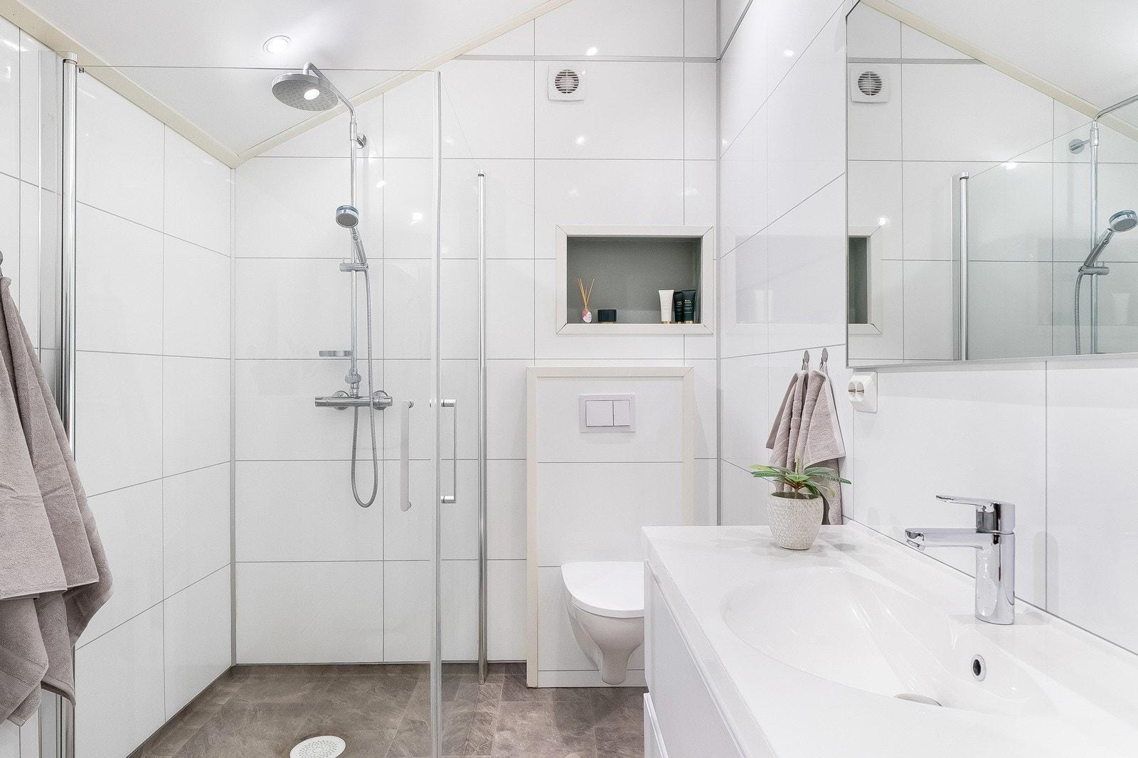 Badet har belegg med varmekabler i gulvet og baderomsplater på veggene, og er innredet med baderomsinnredning, toalett, dusjhjørne og opplegg for vaskemaskin. Galleribilde