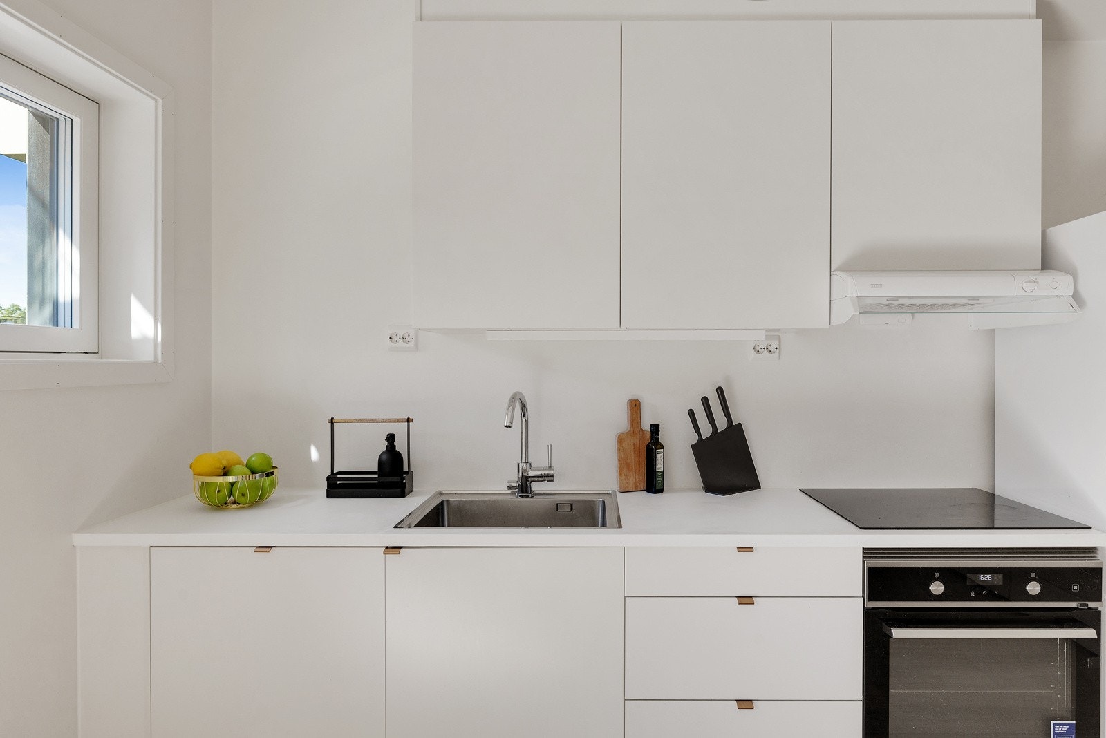 Kjøkkenet er utstyrt med ventilator i overskap og integrerte hvitevarer som platetopp, komfyr og oppvaskmaskin. Galleribilde