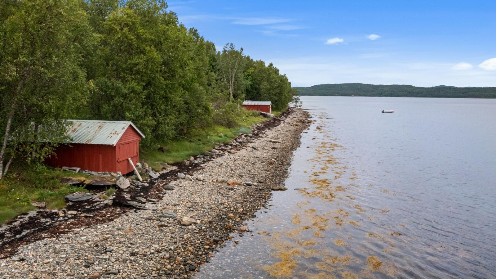 Tomt med strandlinje og to naust.