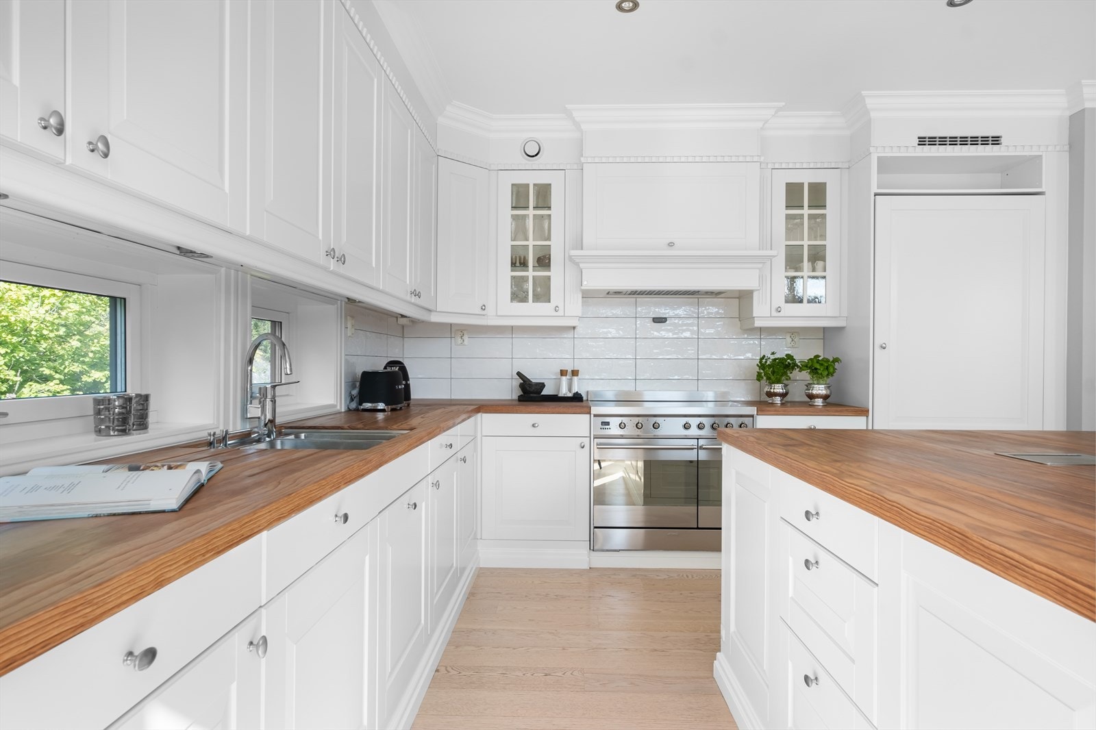 Påkostet og moderne kjøkkeninnredning fra 2014 med benkeplater av heltre, flislagt backsplash, profilerte fronter og ventilator med utkast til friluft. Galleribilde