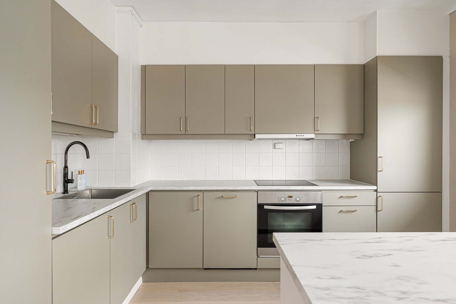 Kjøkkenøy, benkeplate, kjøleskap, oppvaskmaskin og ventilator fra 2020. Galleribilde