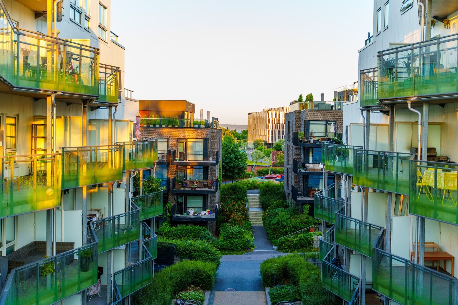 Meget pent opparbeidede og solrike fellesområder med gressplen, trær, beplantning, lekeplass og sittegrupper Galleribilde