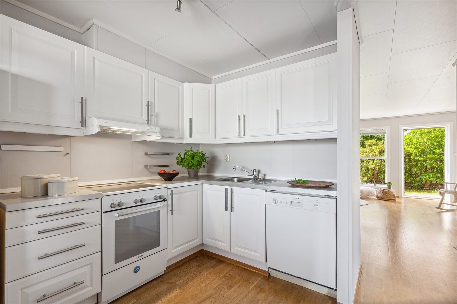 Kjøkkeninnredning fra byggeår med profilerte fronter, benkeplater i laminat, oppvaskkum med ett-greps blandebatteri og ventilator over kokesonen. Galleribilde