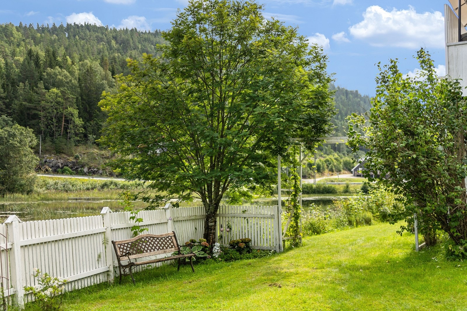 Tomten er meget pent opparbeidet og beplantet med ulike prydbusker, bærbusker, blomsterbed og frukttrær Galleribilde