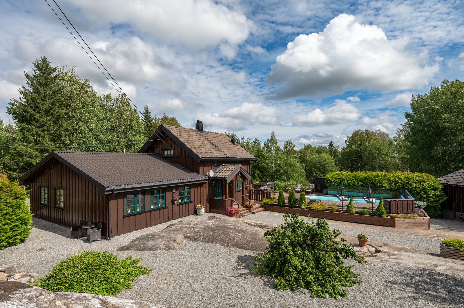Tomten har synlig fjell i dagen, noe naturlig vegetasjon og trær, samt plen og beplantninger. Galleribilde