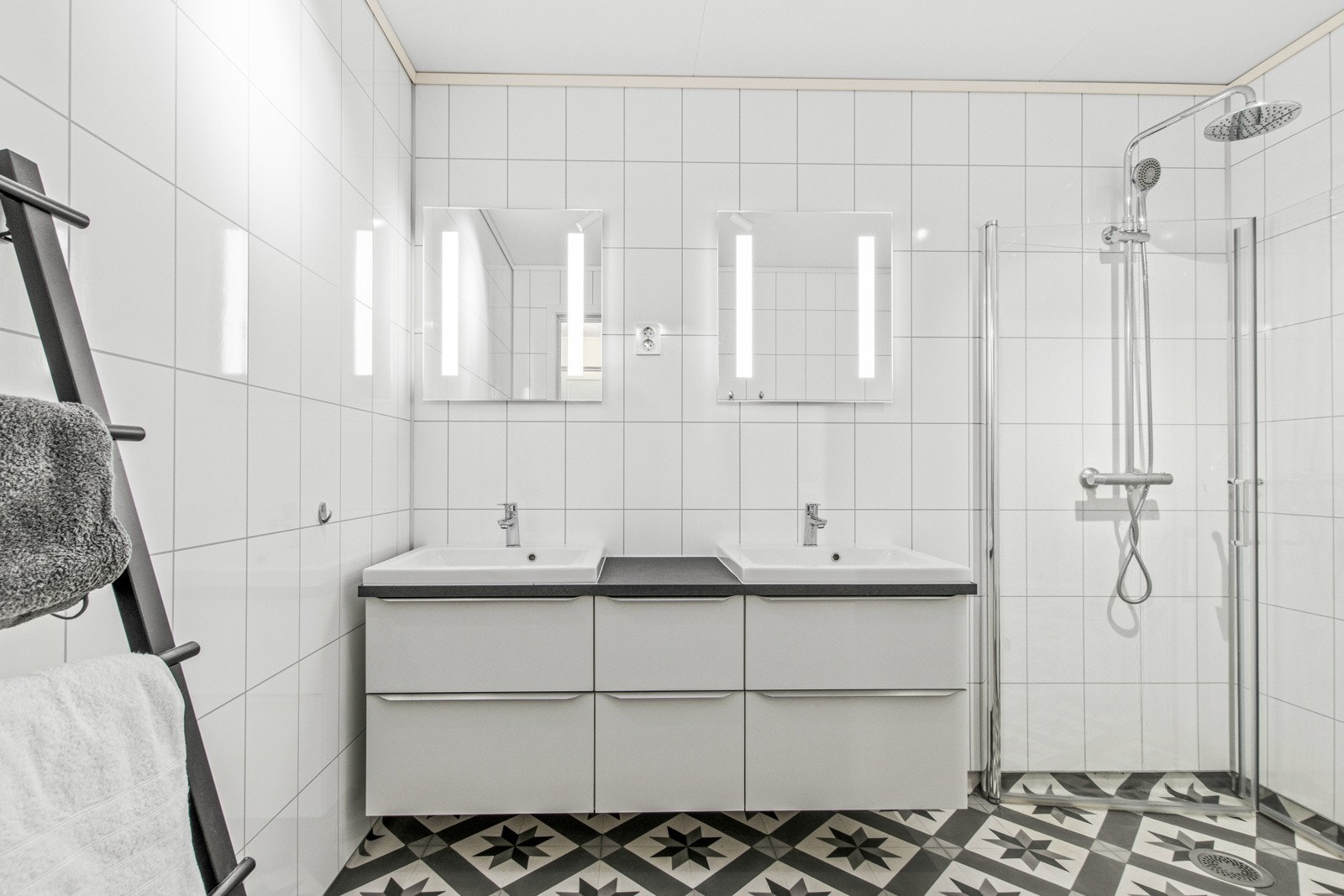 Av utstyr finnes varmekabler i gulv, dusjhjørne med glassdører, dobbel servant og klosett. Galleribilde