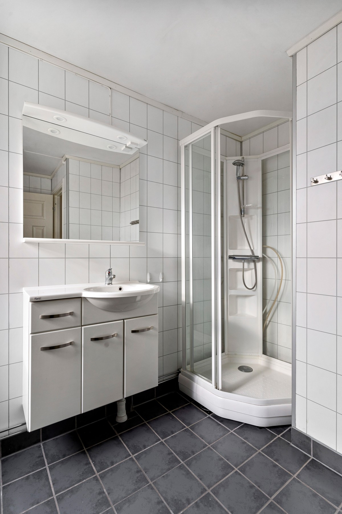 På badet finner du dusjkabinett, servant med underskap og gulvmontert toalett.
