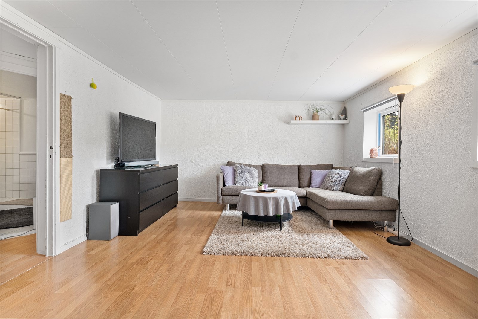 Underetasje innredet med stue og kjøkken i åpen løsning (ikke godkjent). Hvitmalte vegger og laminat på gulv. Galleribilde