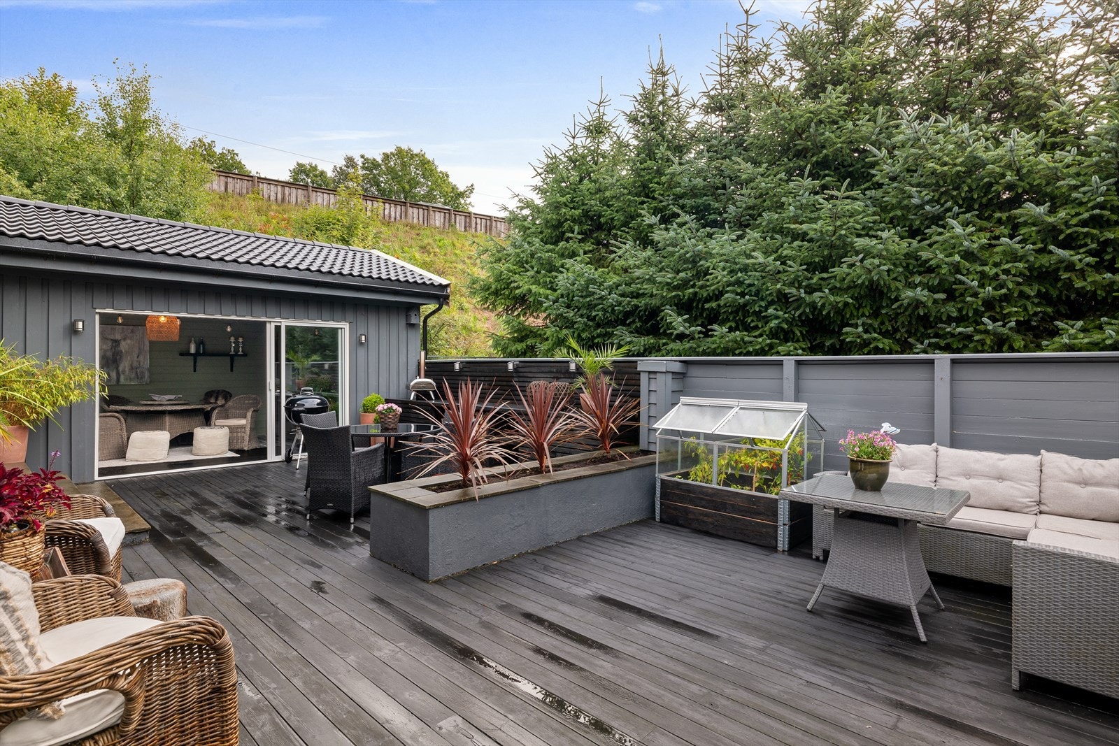 Skjermet terrasse med fine miljø. Det er bygget utekjøkken og plantekasser. Galleribilde