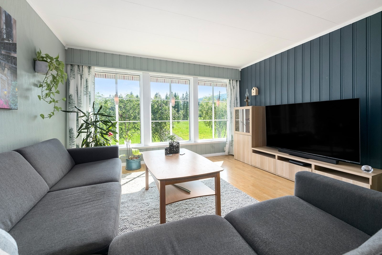 Det første som slår imot deg når du går inn i stuen er den nydelige utsikten. Vindu som går nesten fra gulv til tak langs den ene veggen slipper inn naturen og gjør rommet lyst og trivelig. Galleribilde