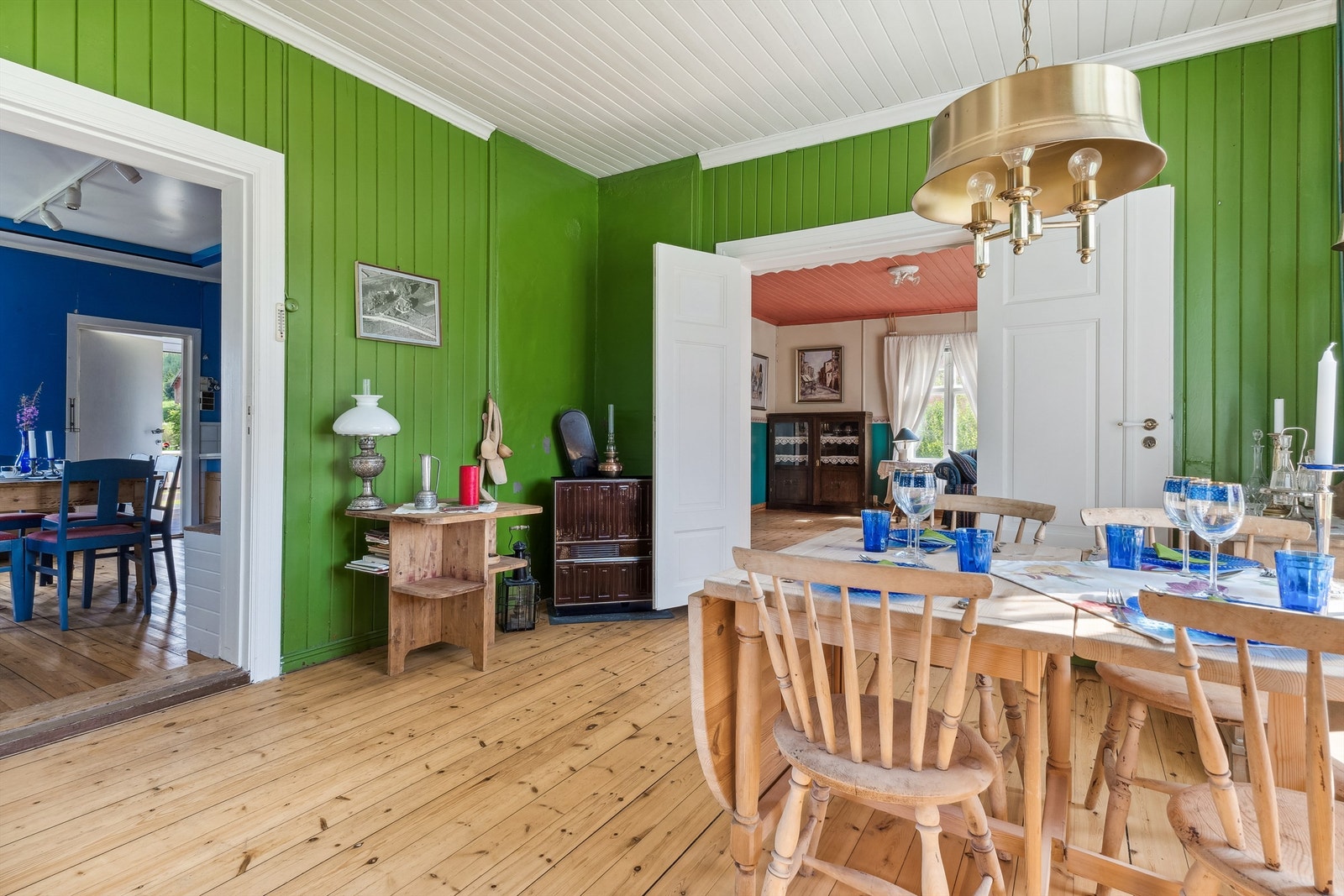 Spisestue med grønnmalt panel på veggene og furugulv. Galleribilde