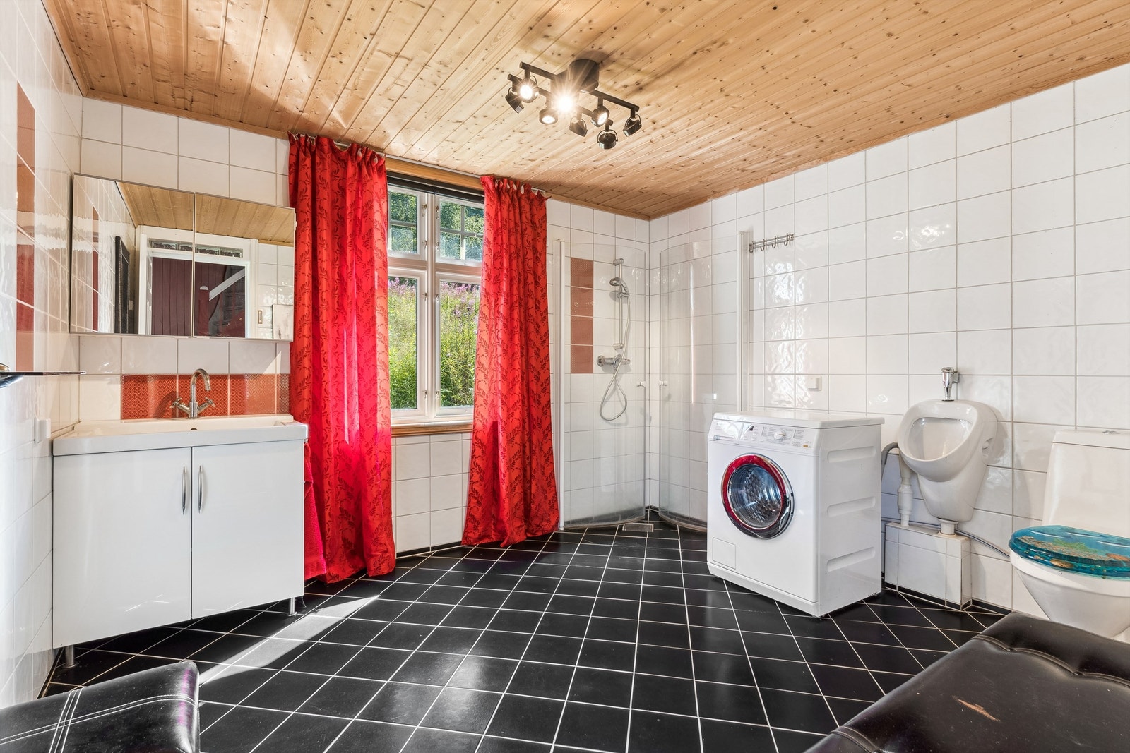 Baderom i 1. etasje med hvite fliser, og noen røde fliser på veggene og svarte fliser på gulvet, samt panel i himling. Galleribilde