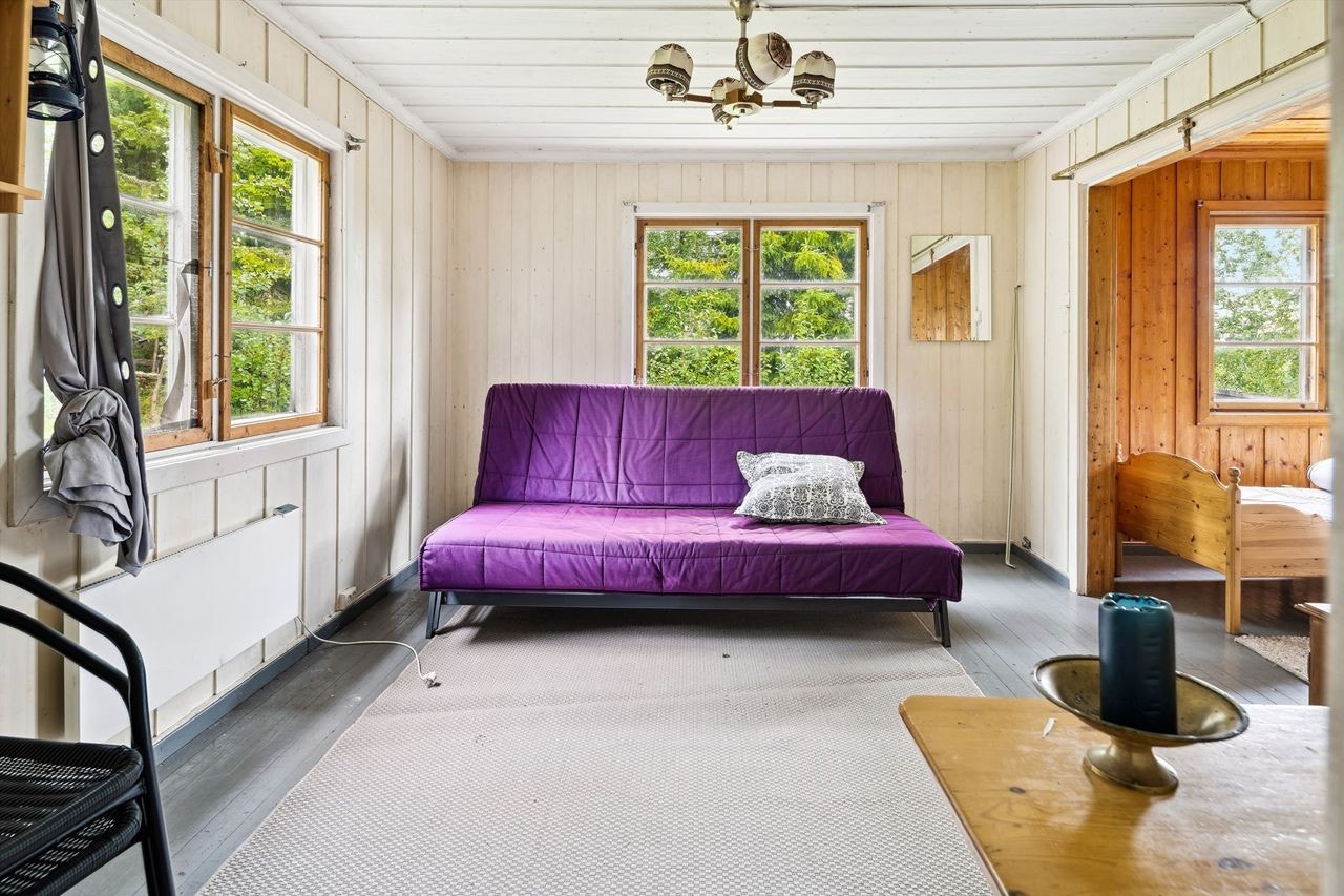 Det er panelovn på veggen som varmekilde. To koblede vinduer slipper dagslyset inn i det lyse rommet. Fra stuen er det adkomst videre til den andre stuedelen. Galleribilde