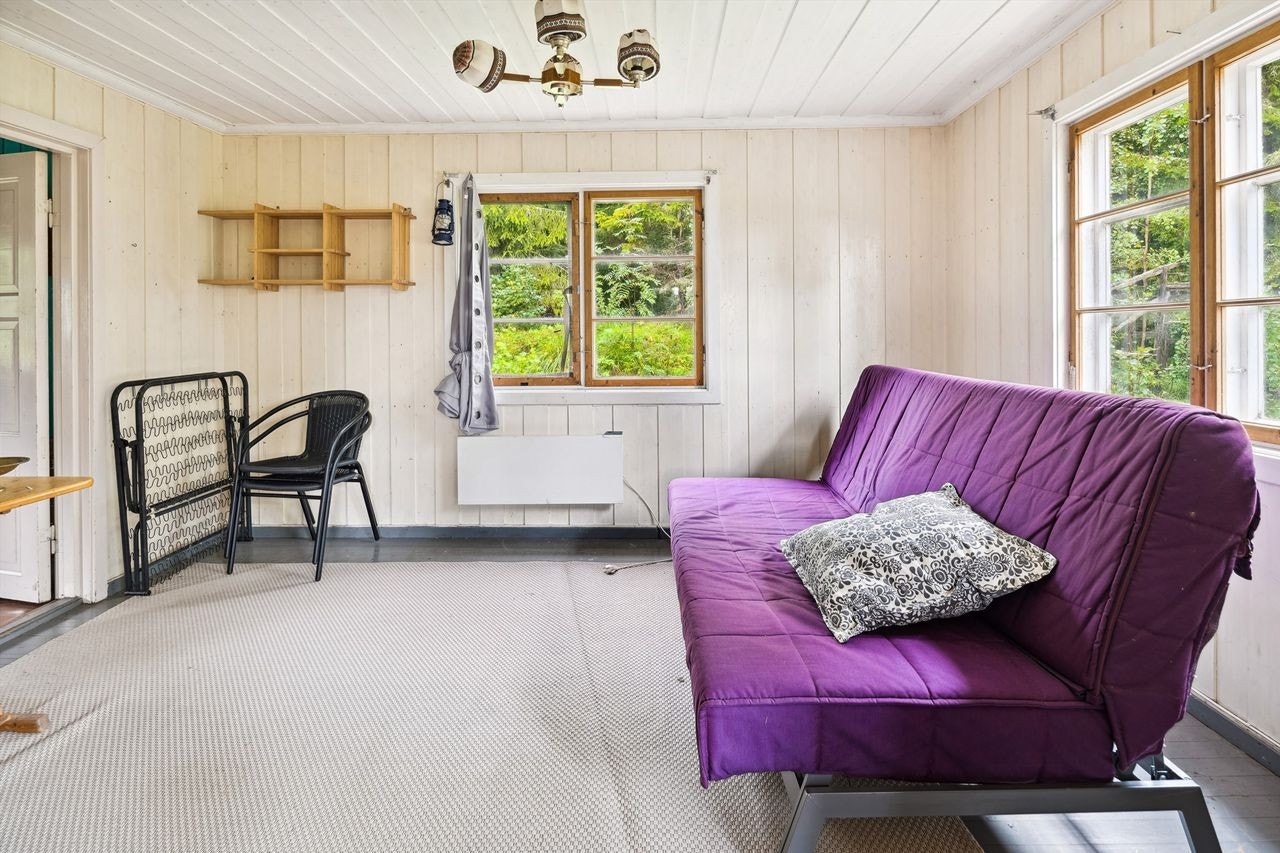 Stue med hvitmalt panel på vegger og i himling, og blå/grå malt tregulv. Rommet er romslig med god plass til å etablere sofagruppe, spisestue eller annet møblement. Galleribilde