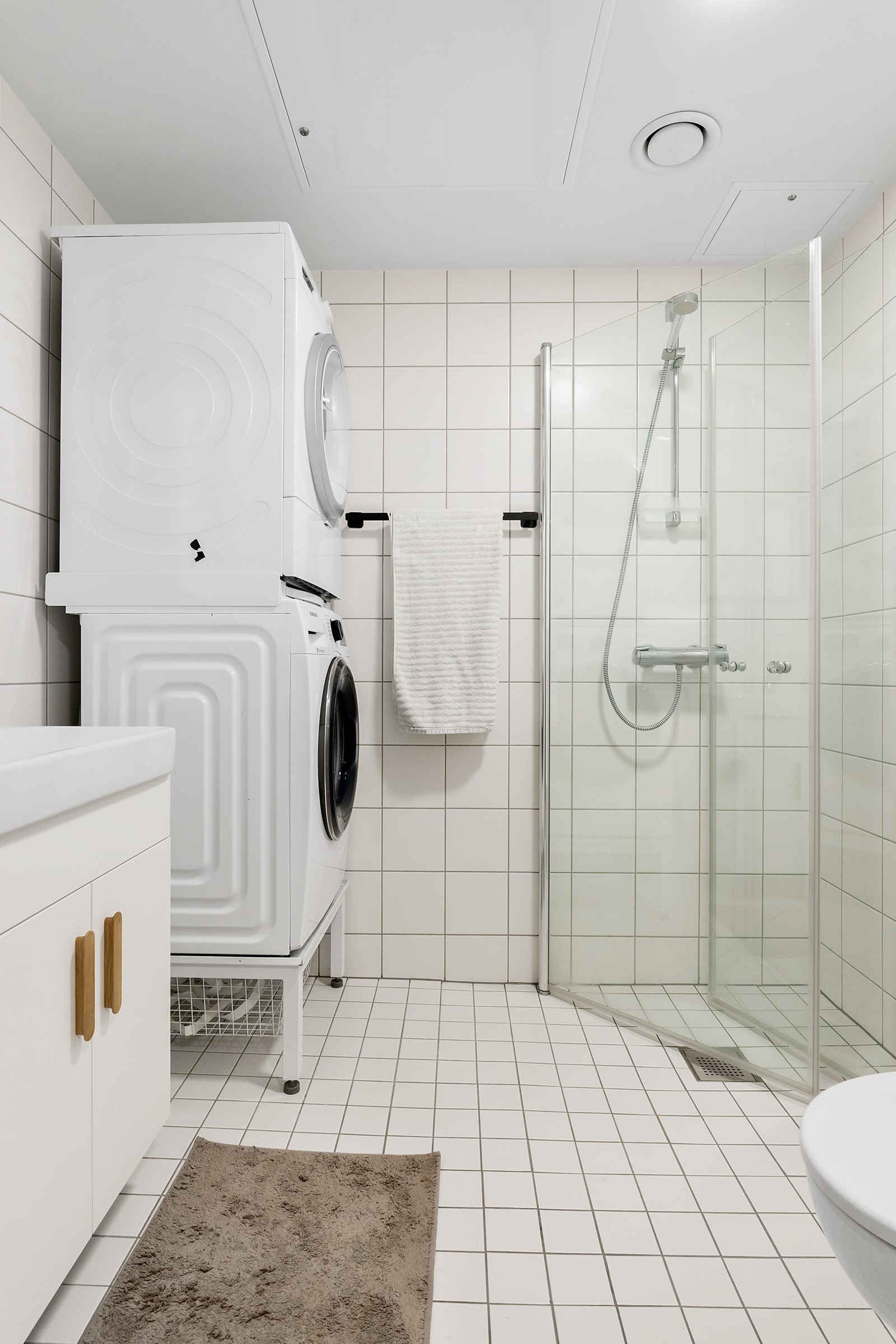 Flislagt bad med dusjhjørne, vannklosett og servant med servantskap Galleribilde