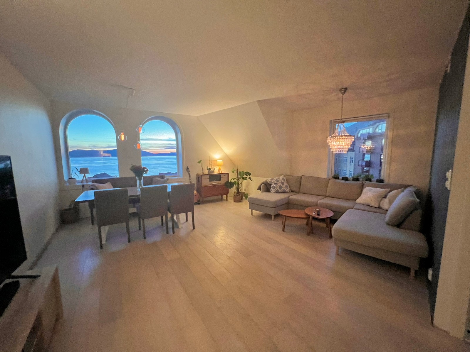 Stuen er moderne, lys og åpen, med stor hjørnesofa, tv og spisestue Galleribilde