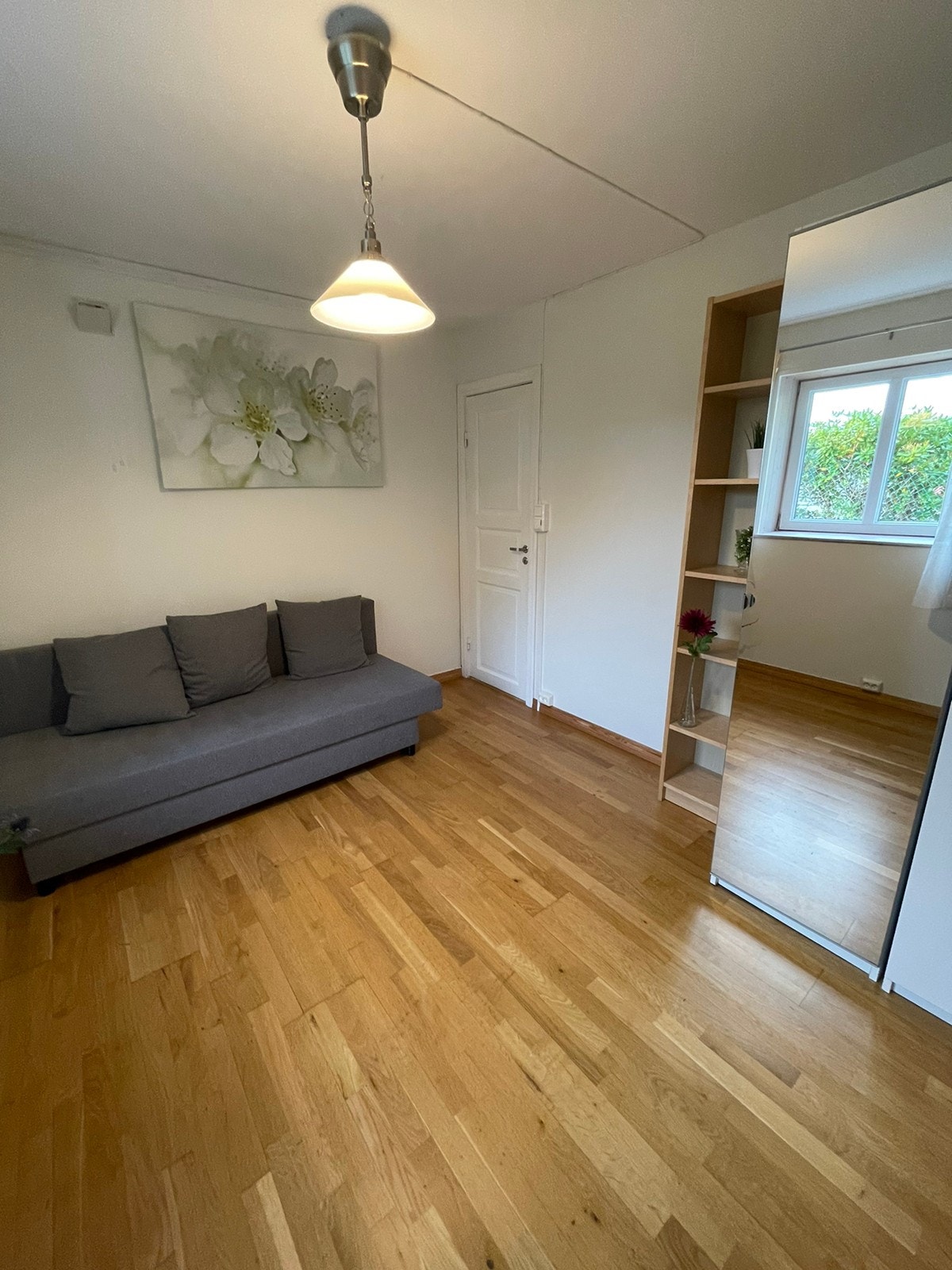 Del av pen stue med parkett og lyse, pene vegger. Sovesofa er kun ment som illustrasjon. Galleribilde