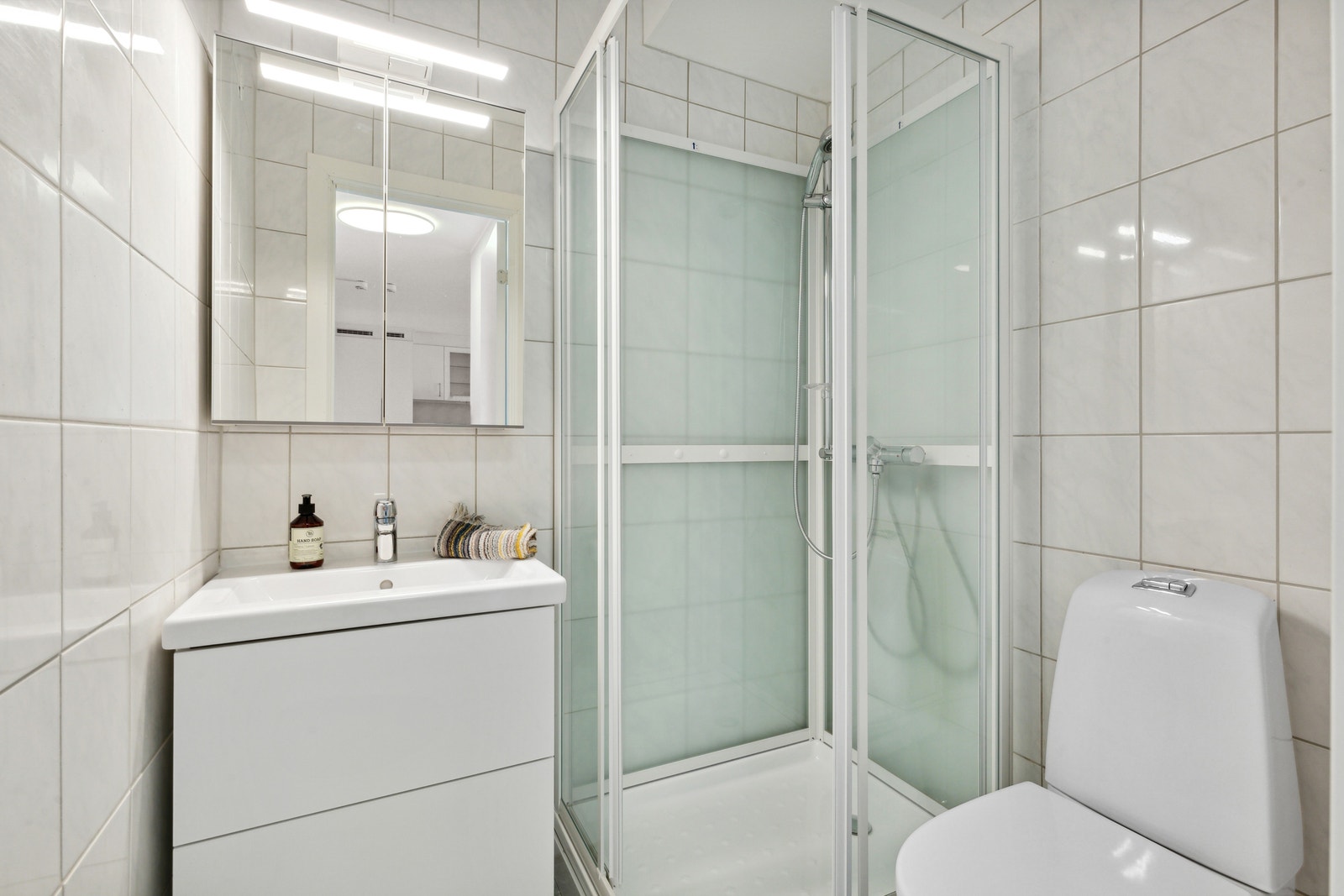 Leilighetens bad - med baderomsinnredning, dusjkabinett og WC Galleribilde