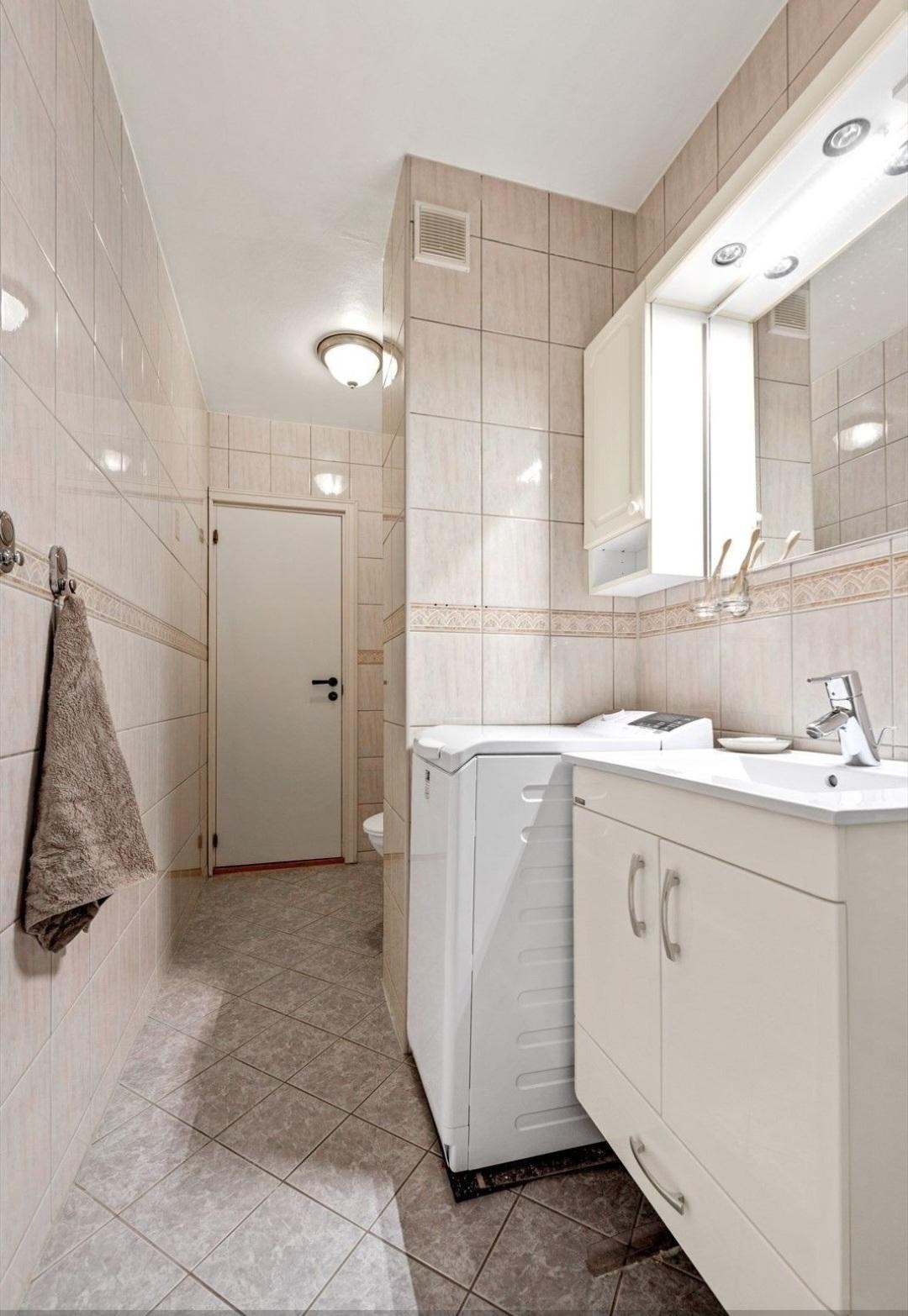Badet er utstyrt med servantskap, speil, dusjsone med glassdører og wc Galleribilde