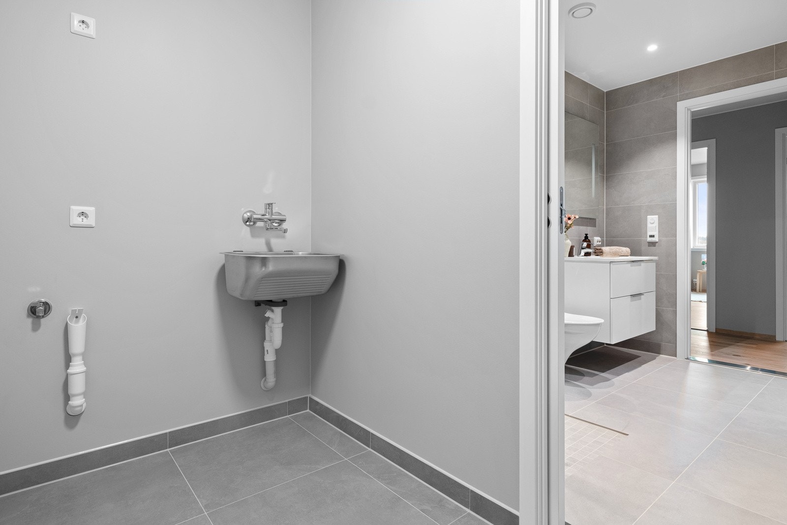 Fra badet er det skyvedør inn til vaskerommet, rommet har fliser på gulvet og slette, malte veggflater. Rommet er utstyrt med opplegg til vaskemaskin og utslagsvask. Galleribilde