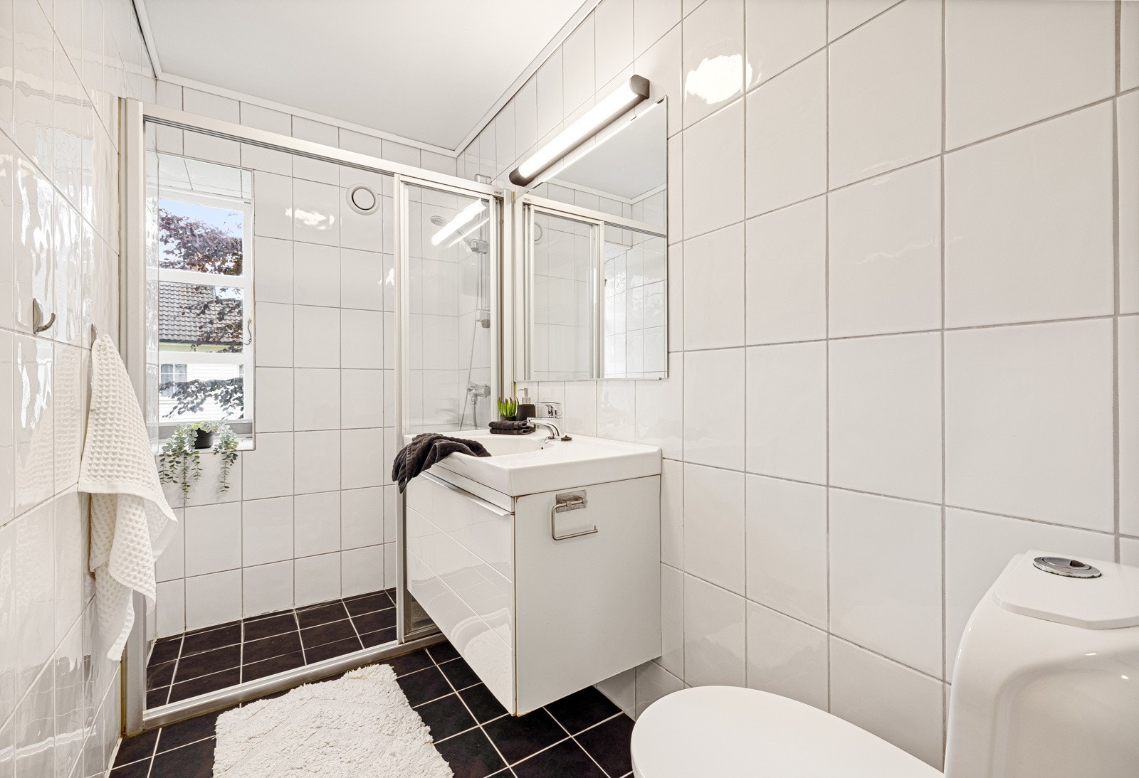 Badet har keramiske fliser på gulv og vegger med en dusjnisje innerst. Galleribilde