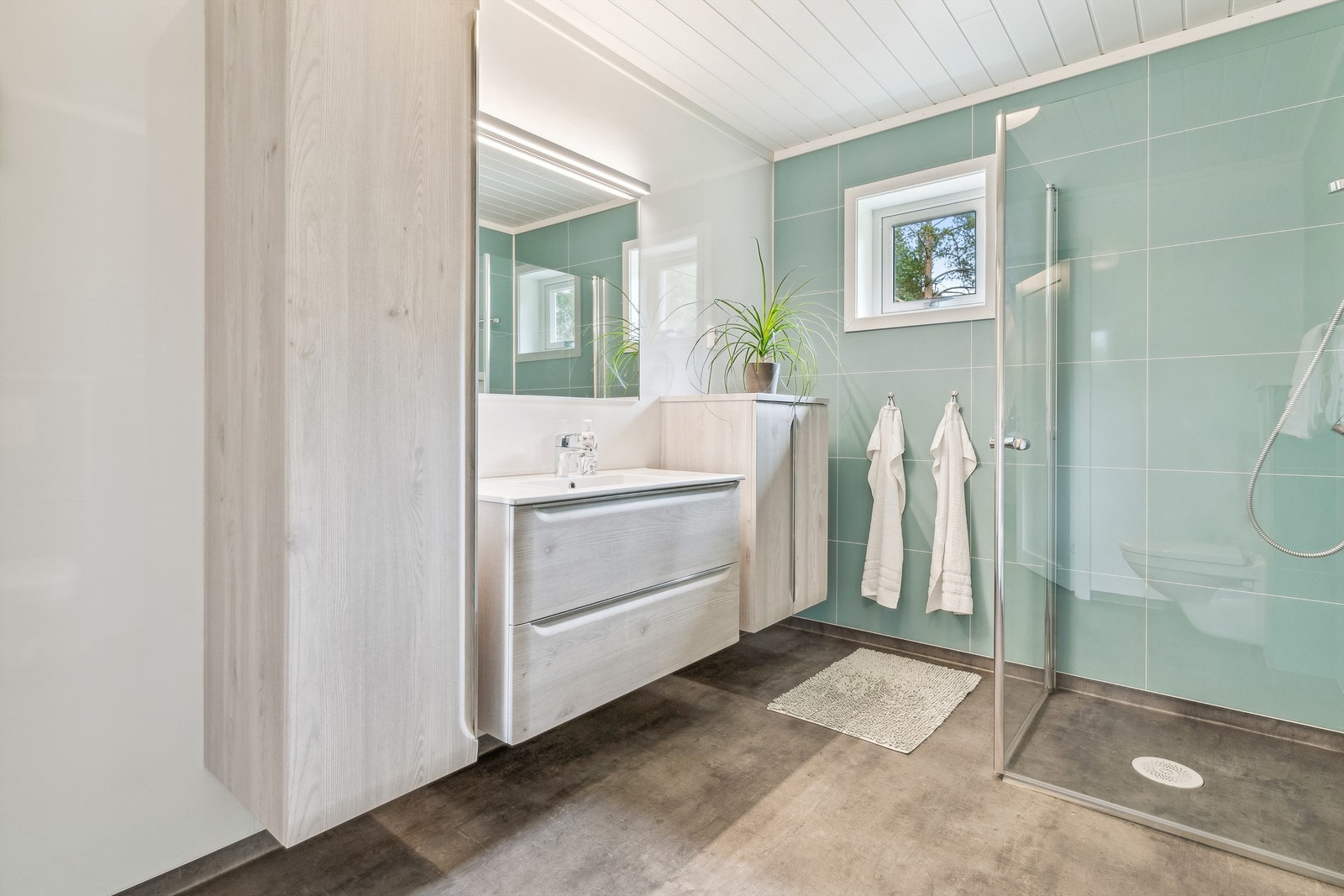 Fresht bad på hovedplan, med våtromsplater i svale, tidsmessige fargetoner. Belegg på gulv. Gulvvarme. Romslig baderomsinnredning. Galleribilde