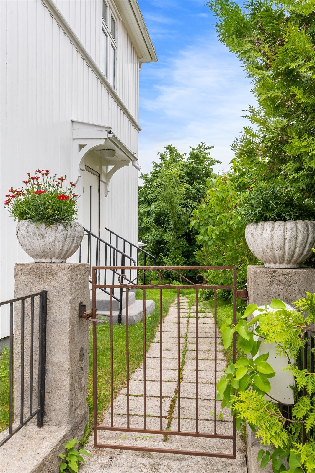 Steinbelagt sti på ene siden av boligen bak en port. Galleribilde