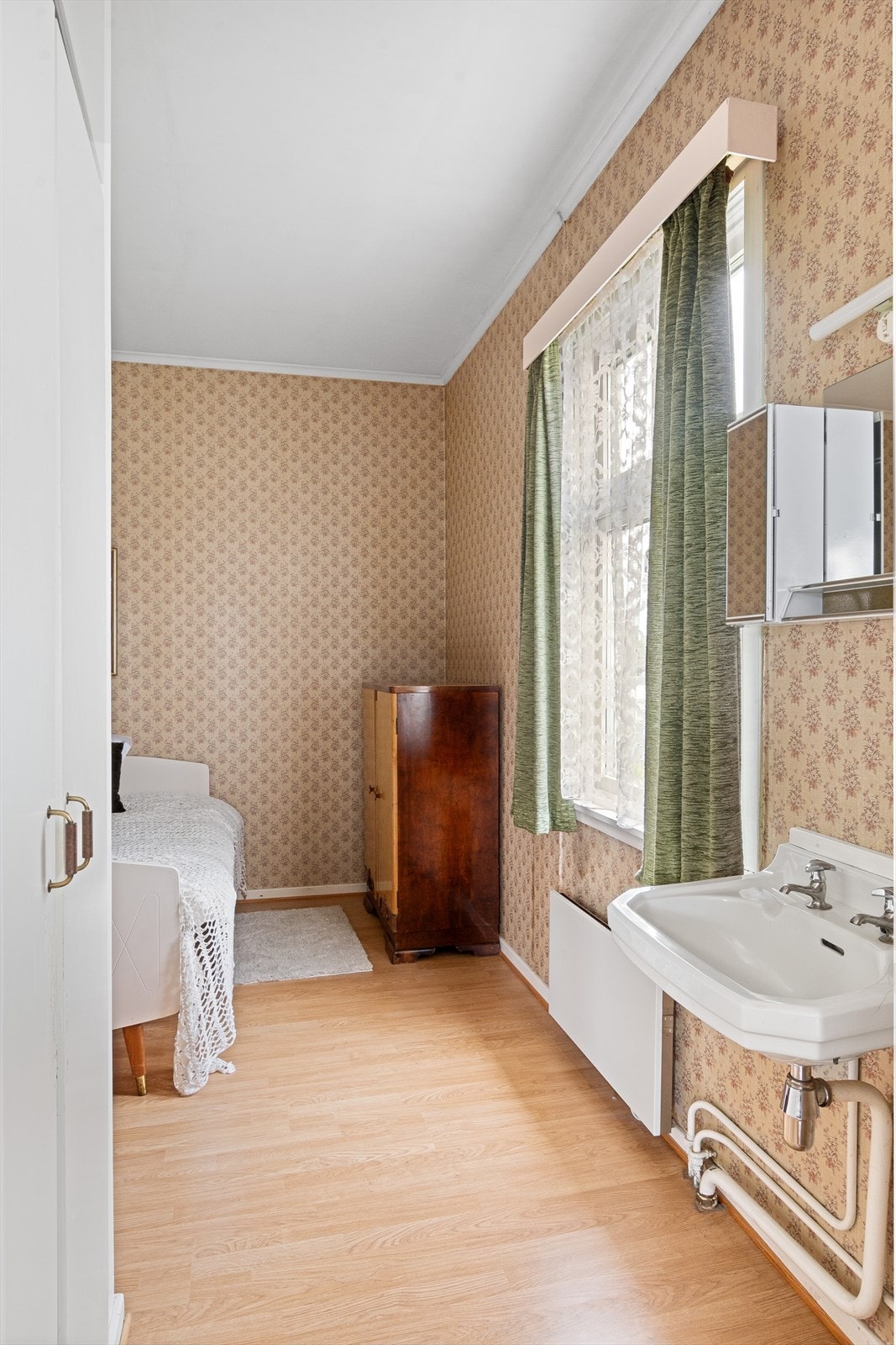 Soverom med mønstrete tapet på veggene og hvitmalt himling. Galleribilde