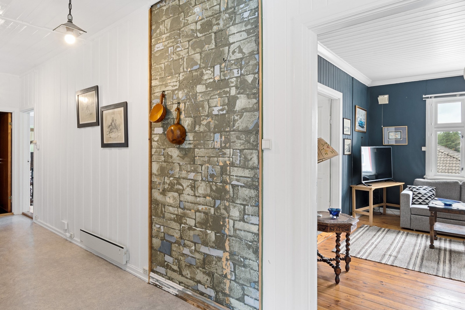 Gangen utenfor peisestuen har panelovn montert på vegg. Galleribilde