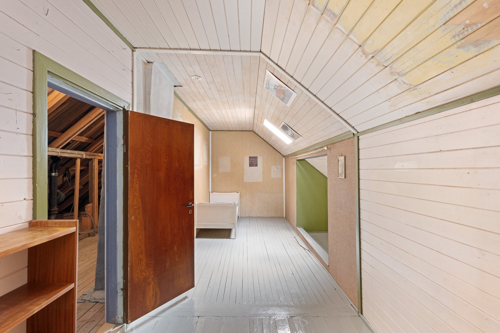 Gangen på loftet med liggende panel på veggene og malt tregulv. Her er det skråhimling og små rom i veggen. Galleribilde
