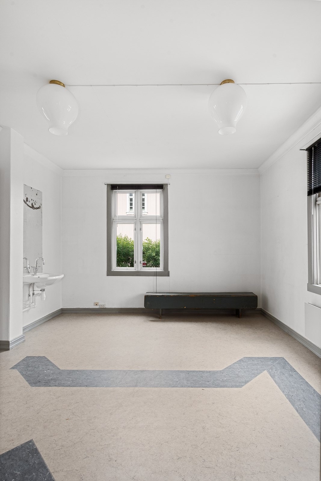 Butikklokalene med grått belegg på gulvet og hvitmalt tapet på veggene. Galleribilde