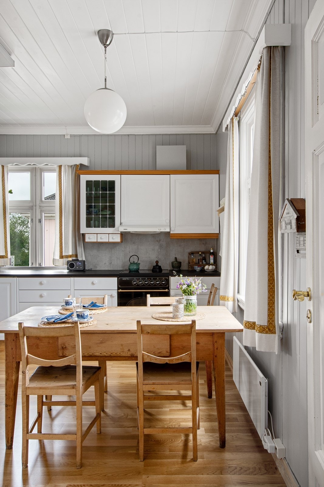 Kjøkken med gråmalt panel på veggene og hvitmalt panel i himling. Galleribilde