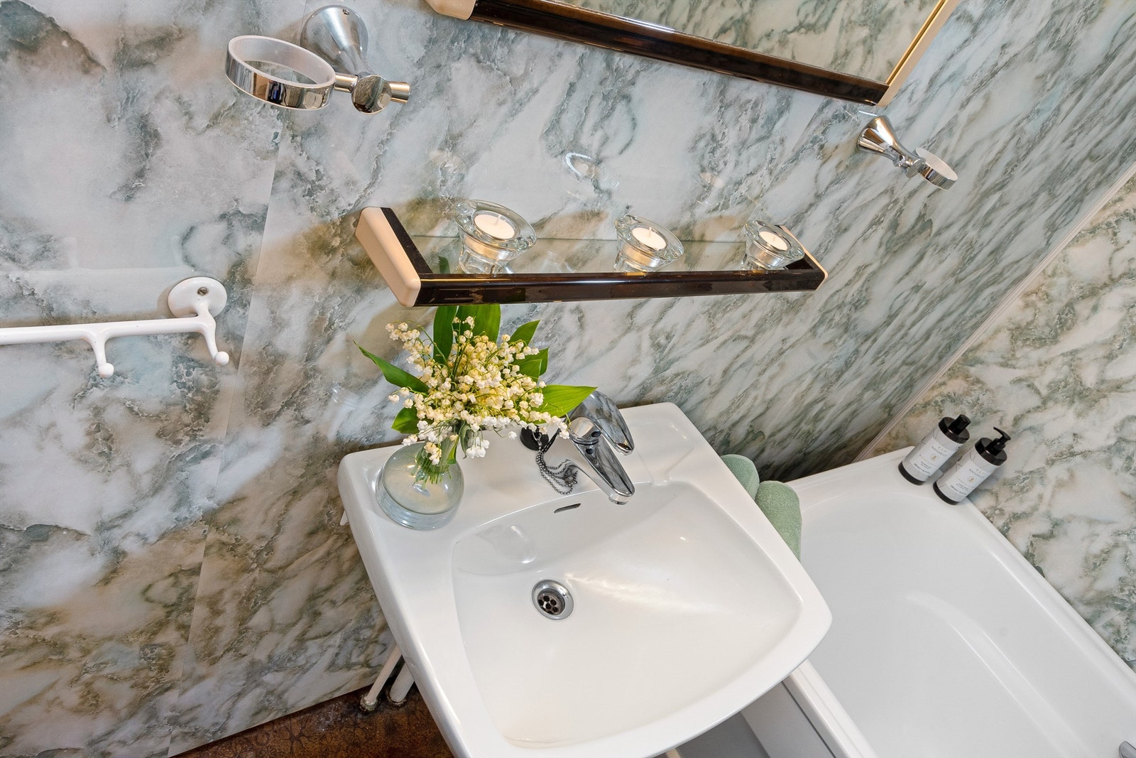 adet er innredet med servant montert på vegg, speil, badekar med dusjforheng og gulvmontert toalett. Galleribilde