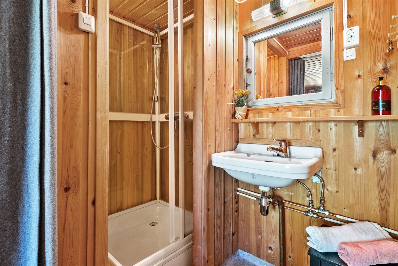 Badet er innredet med vegghengt servant, belyst speil og dusjkabinett i nisje. Galleribilde