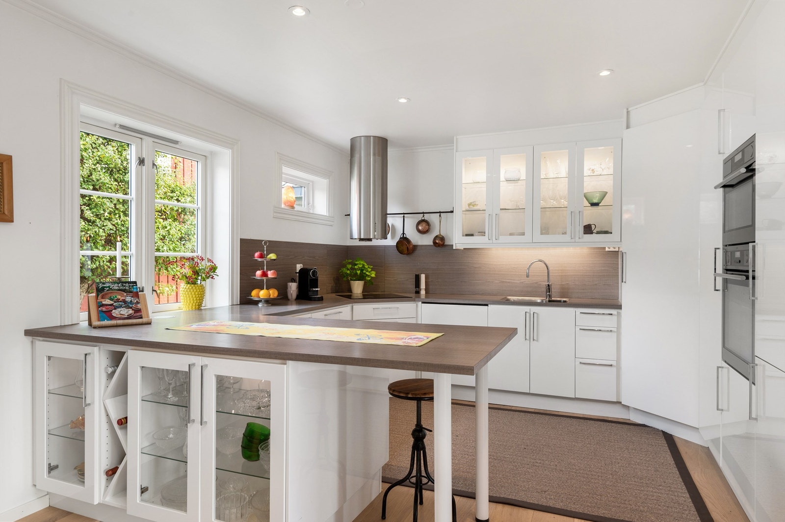 Kjøkkenet måler romslige 20 kvm og er pent innredet med lyse slette flater og benkeplate i mørk kontrast. Her har du også godt med skap og oppbevaringsplass Galleribilde