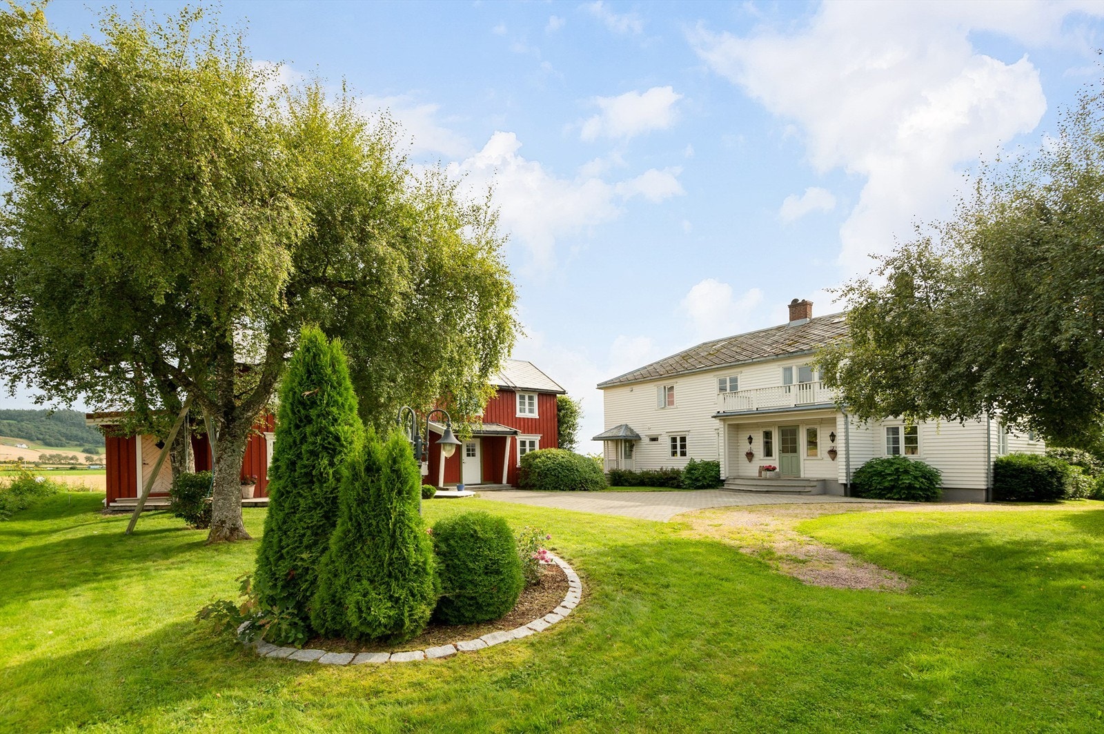 Meget pent opparbeidet gårdstun med store plenarealer, beplantninger, belegningsstein og grus. Stor skiferlagt inngangsparti/trapp. Galleribilde