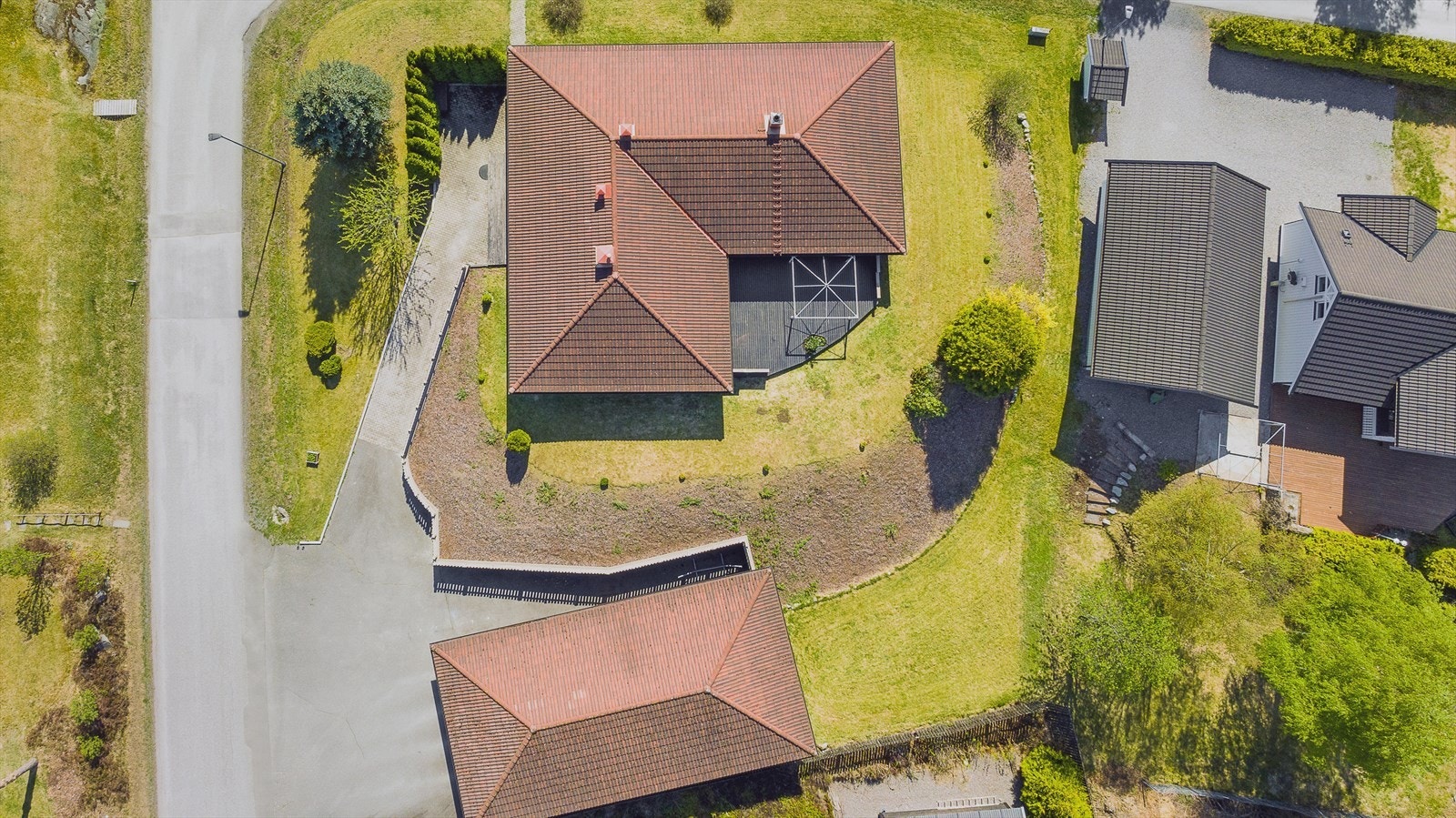 Pent opparbeidet tomt med asfaltert gårdsplass og beplantet hage. Galleribilde