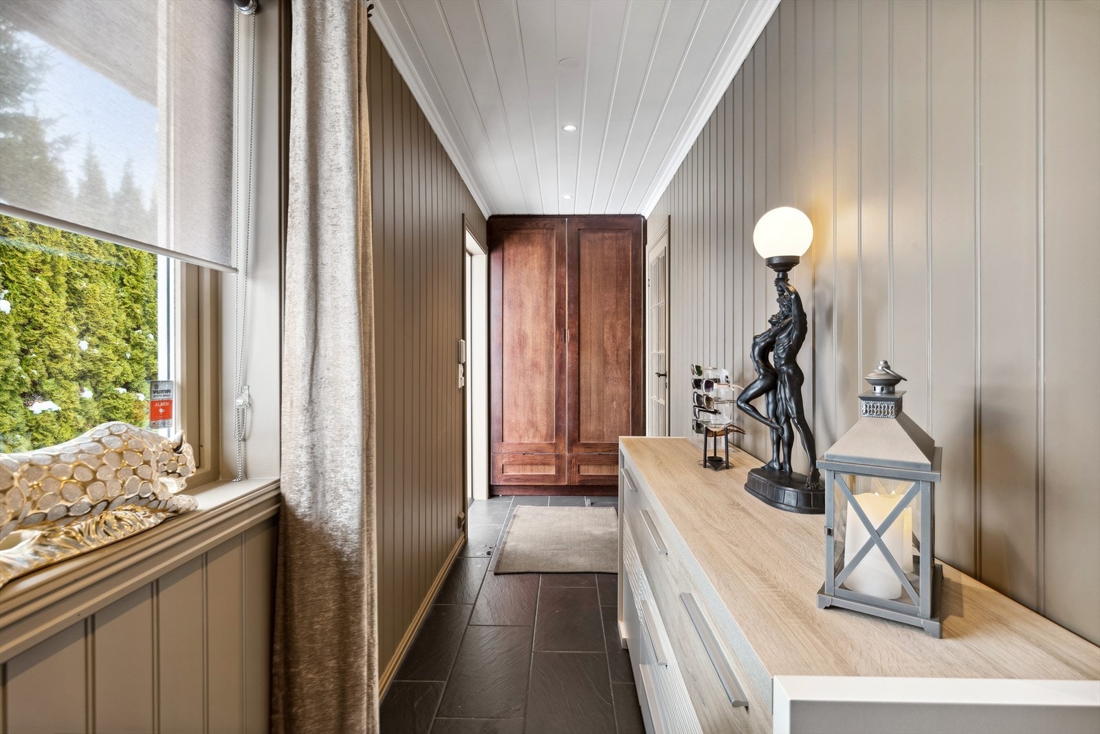 Entréen har lyse overflater på vegg og fliser på gulvet. Praktisk garderobeskap med plass for å henge fra seg yttertøyet. Galleribilde