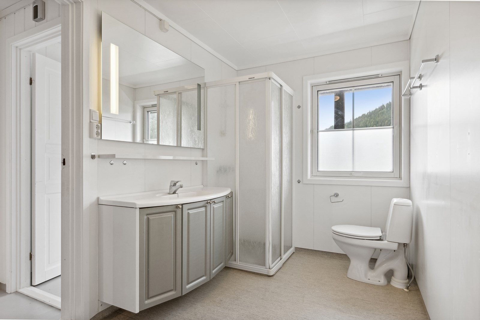 Bad utstyrt med WC, servant med underskap, dusjhjørne og opplegg for vaskemaskin. Galleribilde