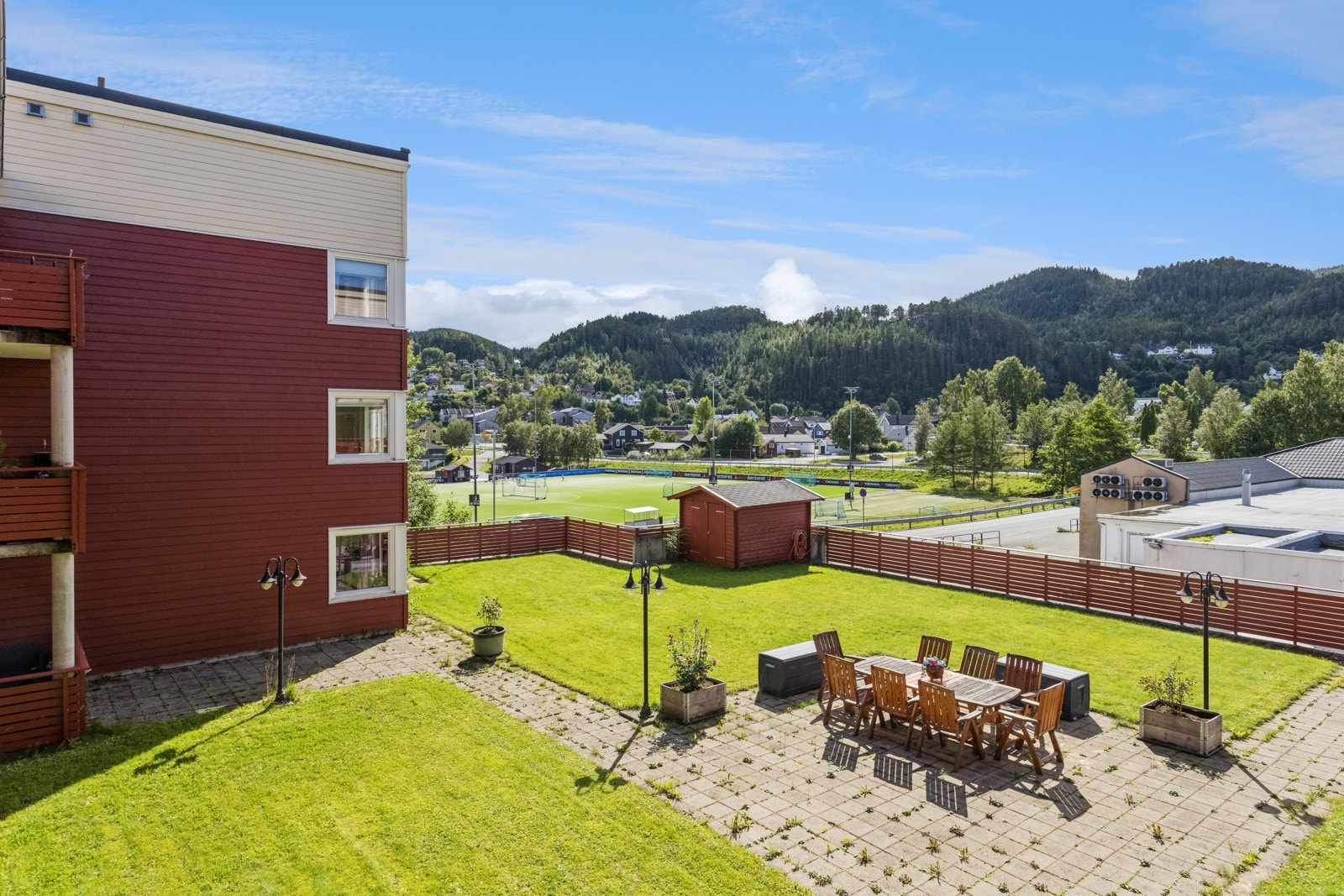 En sjarmerende felles uteplass på toppen av garasjeanlegget inviterer til hyggelige stunder. I sommermånedene prydes området av grønt gress og komfortable sittegrupper for beboerne. Galleribilde