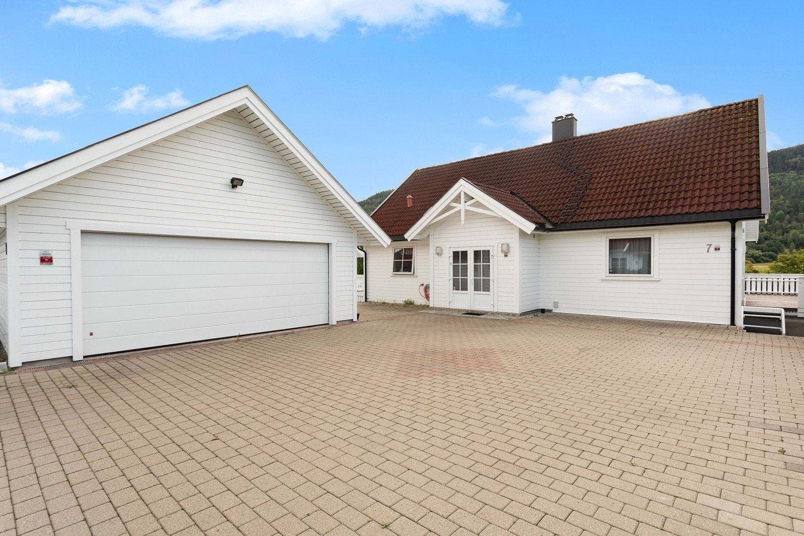 Dobbelgarasje med bod og steinlagt gårdsplass. Galleribilde