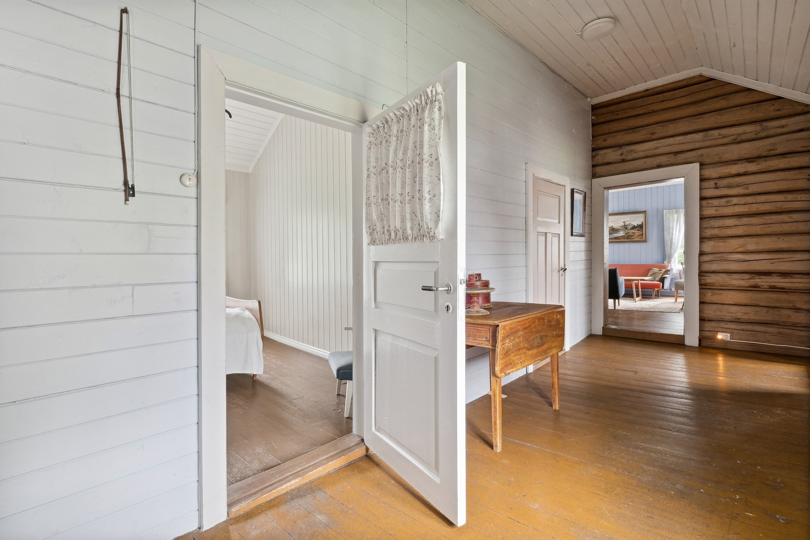 Innergang i 2. etasje med hvitmalt panel og tømmer på veggene og furugulv. Galleribilde