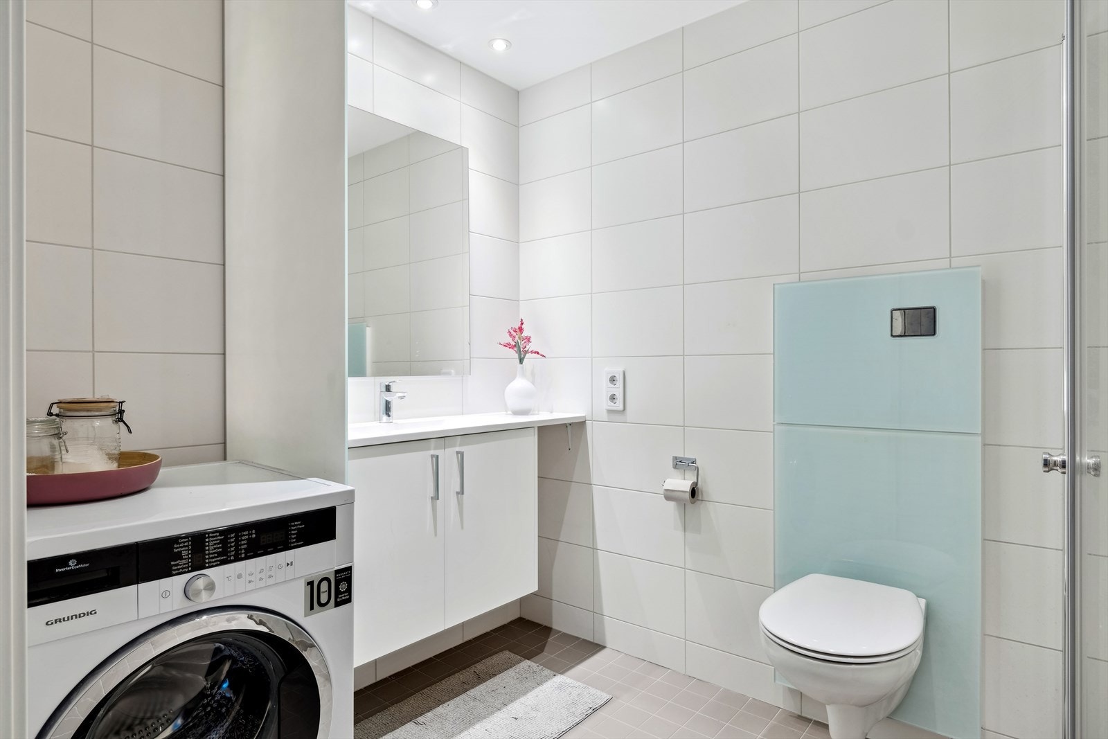 Badet er utstyrt med servant med underskap, vegghengt toalett, dusjhjørne og opplegg for vask/tørk. Galleribilde