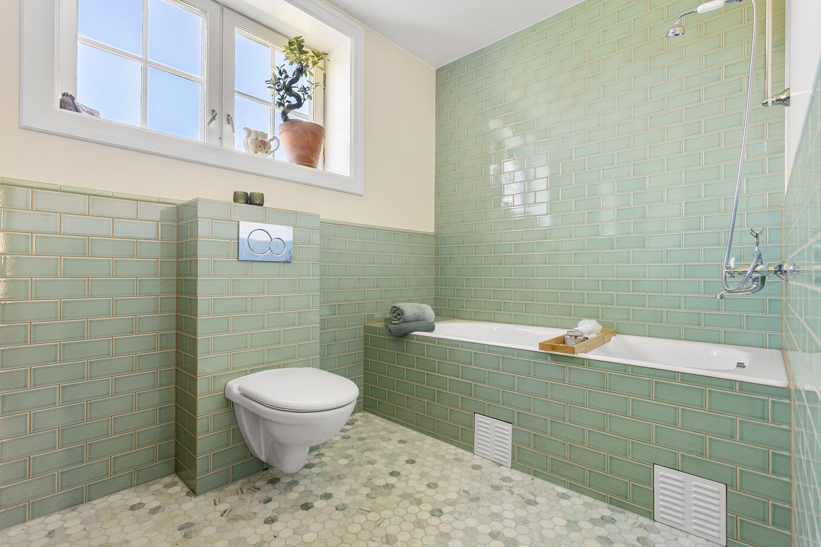 Badet er utstyrt med vegghengt wc, servant med skap under og dusj i hjørne med innmurt badekar. Begge badene har retro fliser fra Fired Earth og innredning fra blant annet Jacob Delafont. Galleribilde