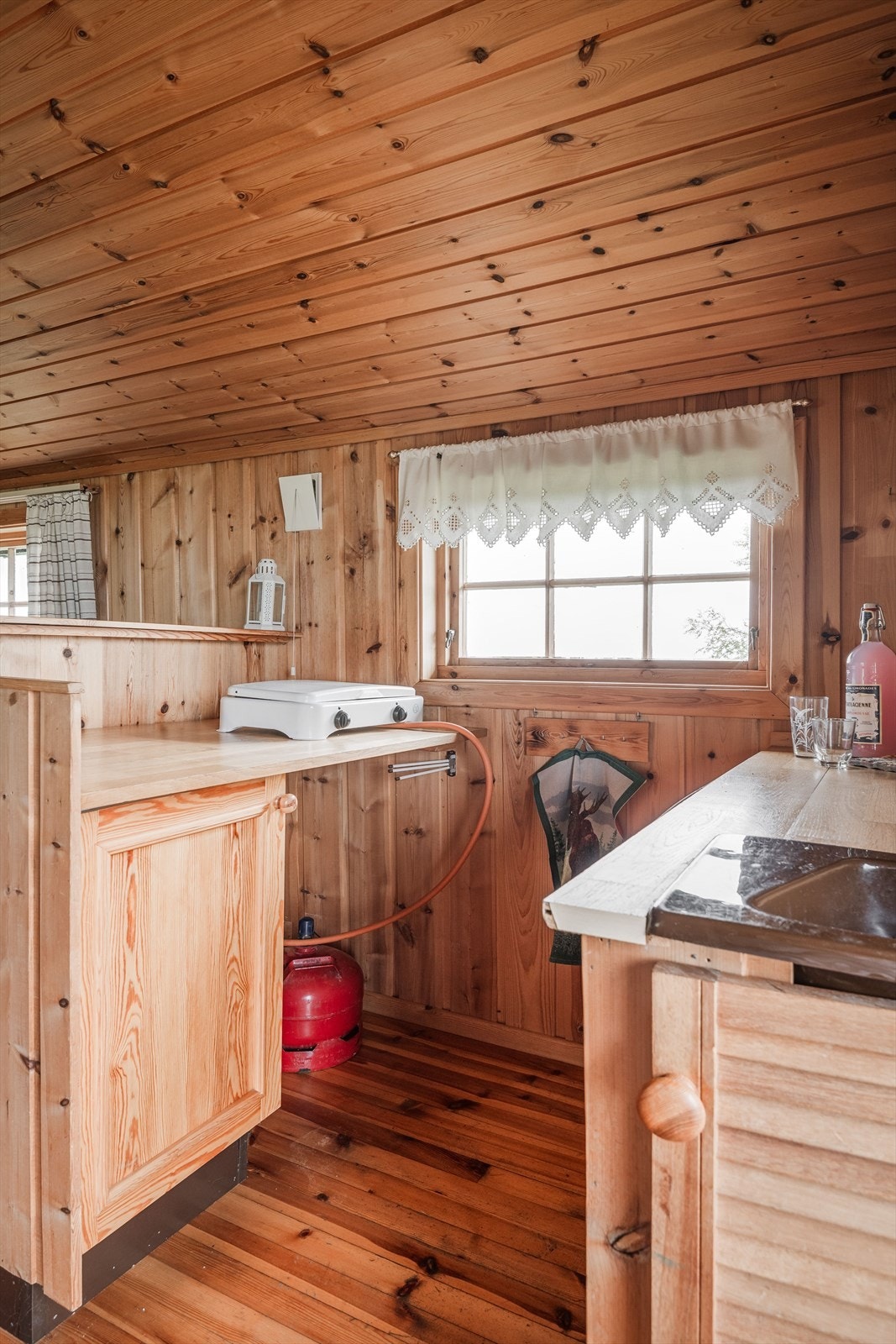 Kjøkkeninnredning med underskap, ett overskap. speil fronter, plastkum og laminert benkeplate. Gråvann føres ut i terreng. Galleribilde