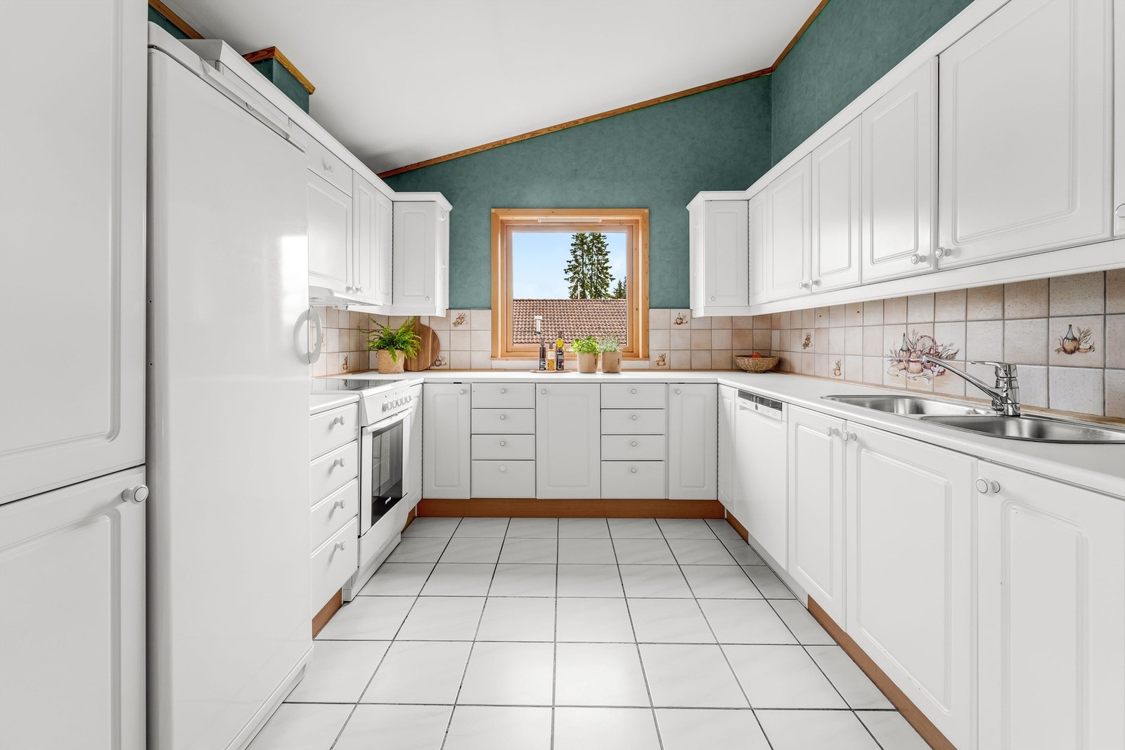 Gulvet i kjøkkensonen er flislagt og kjøkkeninnredningen er montert i U-form med god skap- og benkeplass. Galleribilde