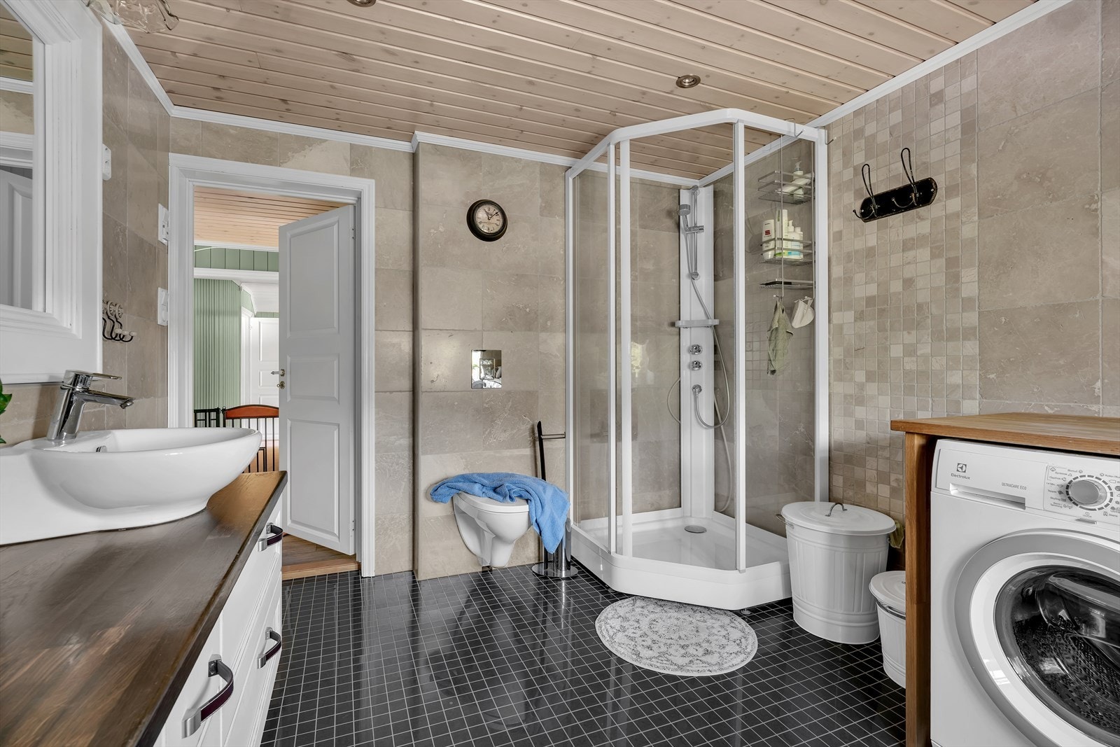 Badet er utstyrt med vegghengt toalett og dusjkabinett. Opplegg for vaskemaskin. Galleribilde